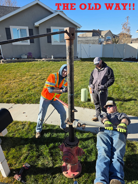 The Old Way — three workers struggling with improvised lever to remove hydrant seat