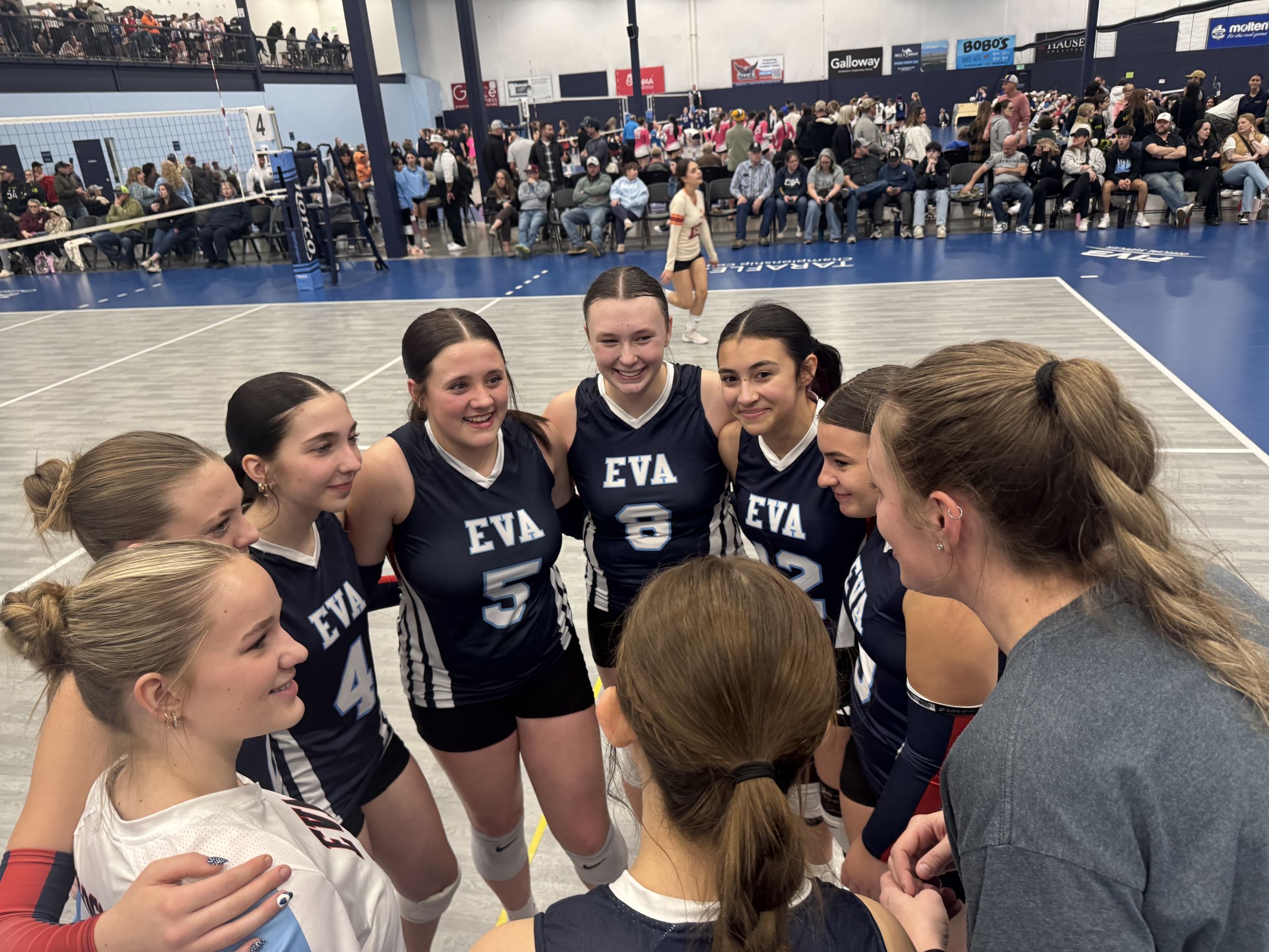 Eaton Volleyball Academy players smiling together in a huddle